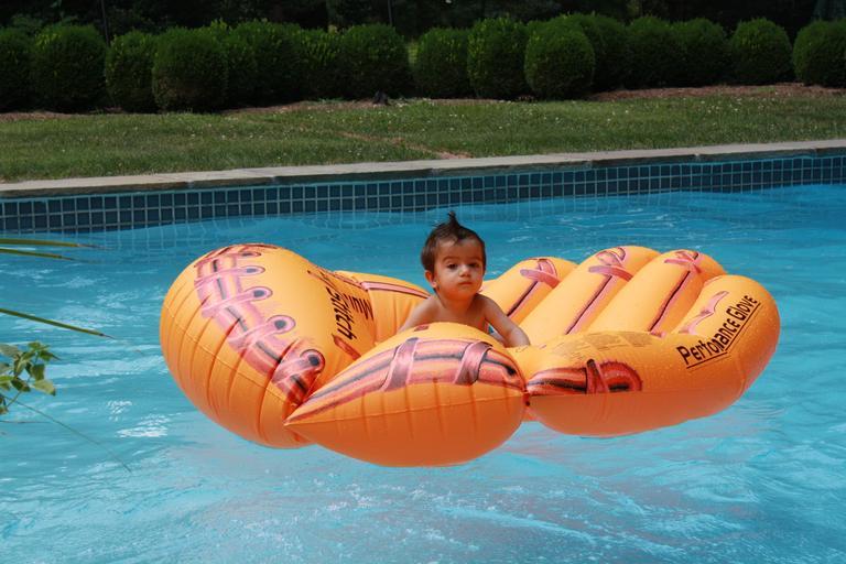 malé dítě v bazénu na oranžovém lehátku